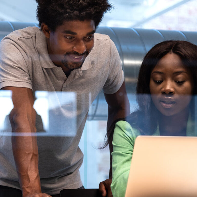 two african american coworkers analyse reports together office using laptop